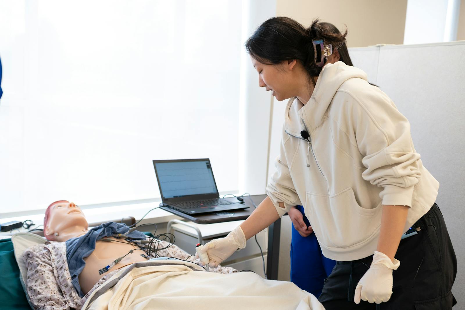 Student working with an instructor during a medical simulation training session.