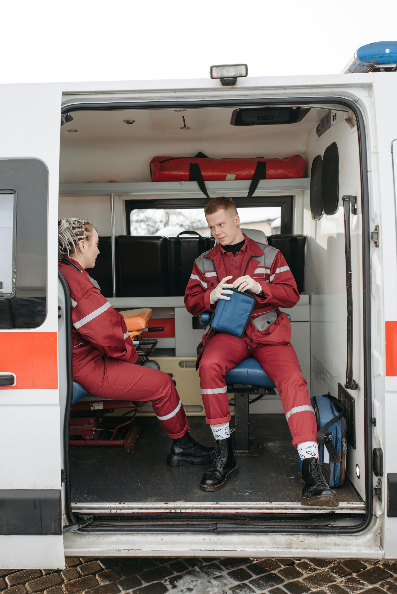 Two paramedic trainees reviewing equipment inside an ambulance during instruction.